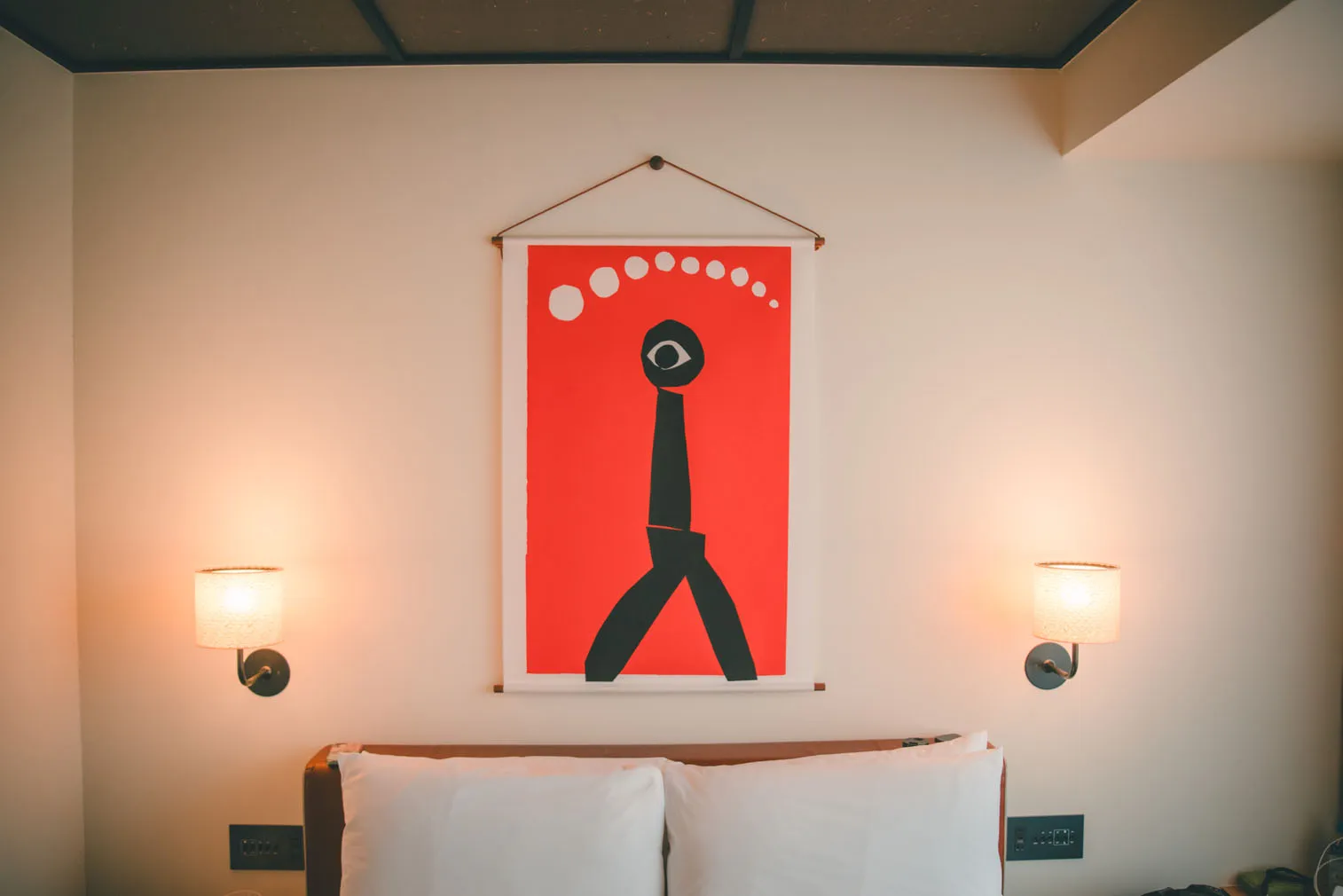 白い壁の部屋に、赤い塔の絵が掛けられている写真